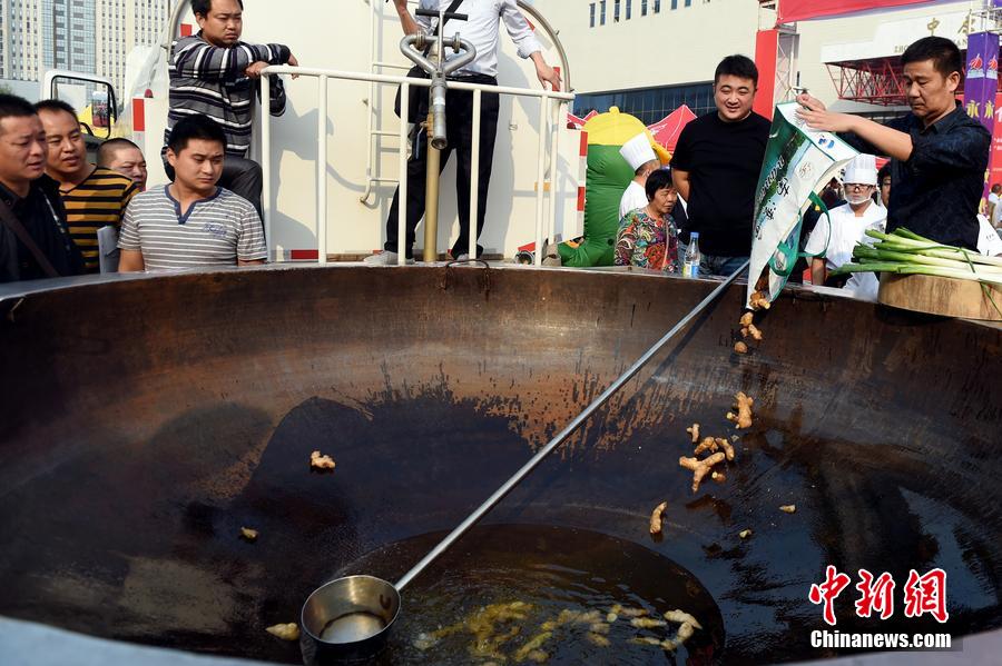 工作人員向大鍋內(nèi)加入油和姜等烹飪調(diào)料。 圖片來源：CFP視覺中國(guó)