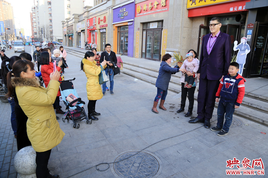 過路市民爭相與“巨人”合影。