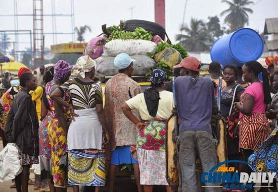 當(dāng)?shù)貢r(shí)間2014年8月14日，利比里亞蒙羅維亞，市場(chǎng)里的商人們圍著一輛汽車。