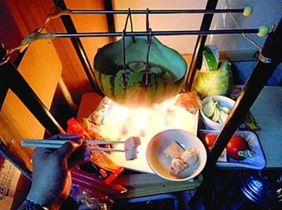 兩張椅子被面對面疊在一起，穿了兩根線的西瓜皮就懸空在椅腳中間，下面有蠟燭加熱，這就是西瓜火鍋。