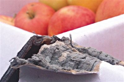 8月29日，新發(fā)地市場(chǎng)，一箱用“加重紙箱”包裝的蘋果正待售，紙箱夾層內(nèi)灰黑色的增重填充物清晰可見