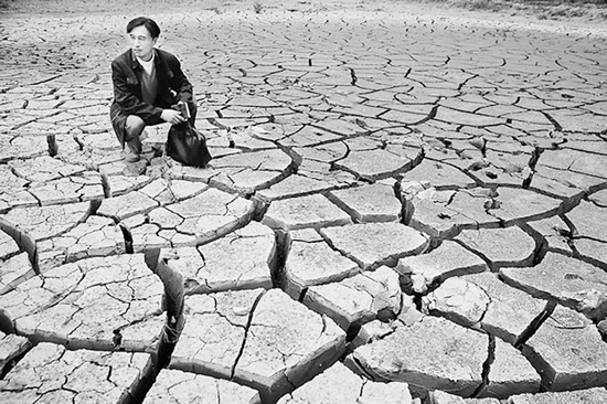 蹲在干涸的田地里，焦裕祿為饑餓的百姓揪心不已 《焦裕祿》劇照